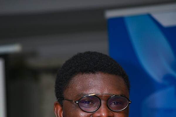 A man in dark glasses speaking into a microphone