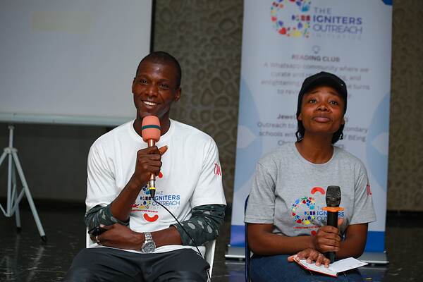 A young man and a young woman seated with microphones, taking questions