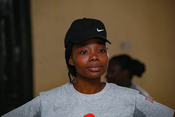 A young woman in a black cap looking toward the front of the room