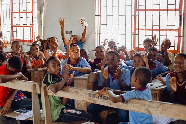 A classroom of students with their hands up