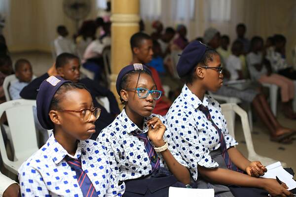 Three schoolgirls in uniform listening from their seats